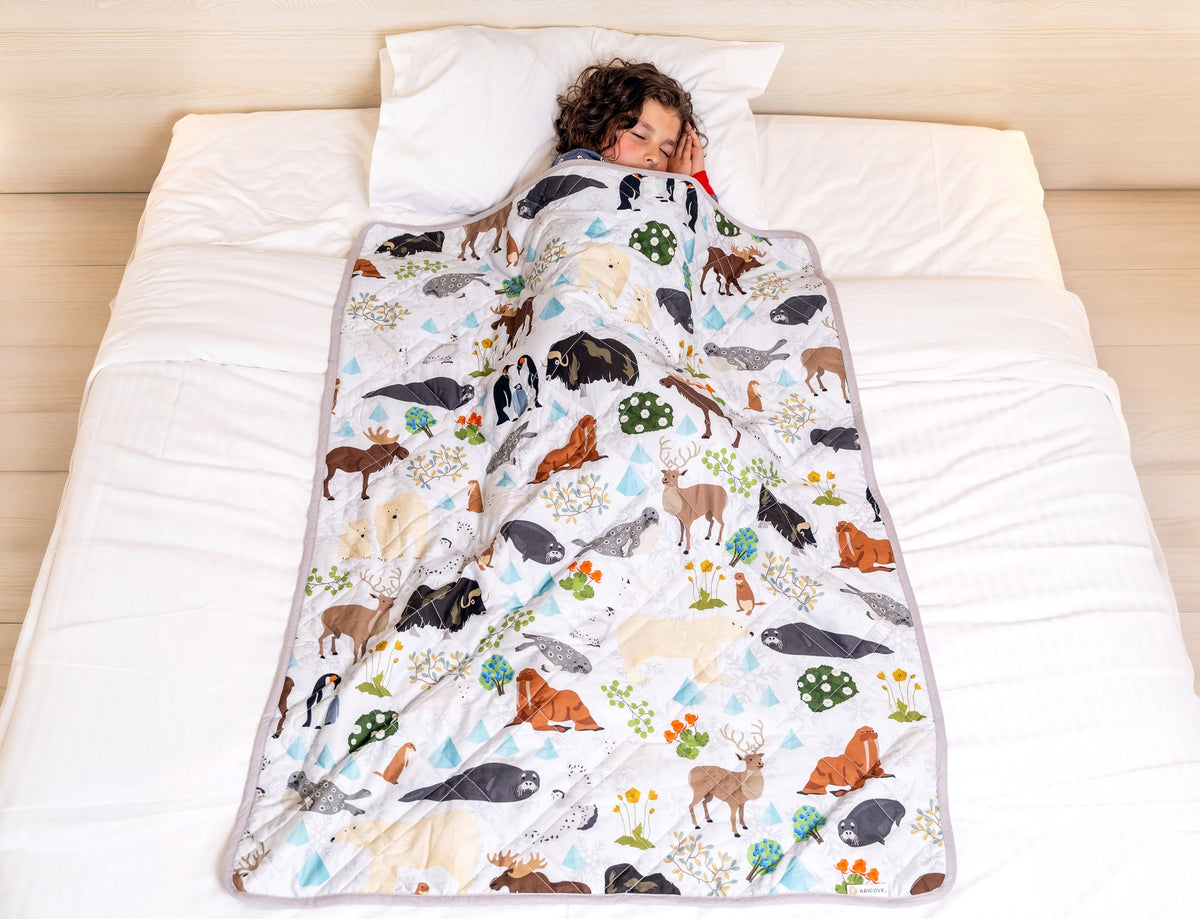 Child asleep under the Aricove kids weighted blanket in the Snow print
