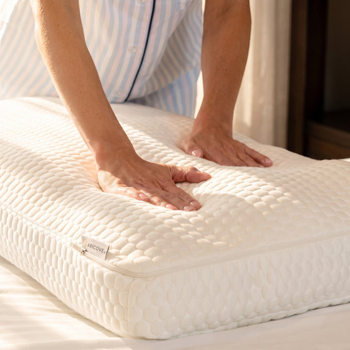 Hands pressing down on an Aricove pillow to test its firmness